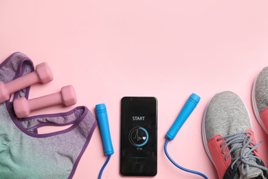 Photo of Smartphone with heart rate monitor app and fitness accessories on pink background, flat lay