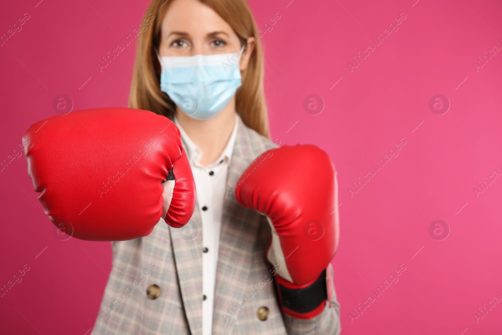 Photo of Businesswoman with protective mask and boxing gloves on pink background, space for text. Strong immunity concept