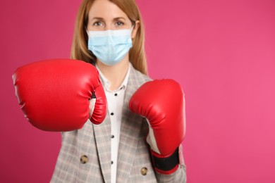 Photo of Businesswoman with protective mask and boxing gloves on pink background, space for text. Strong immunity concept