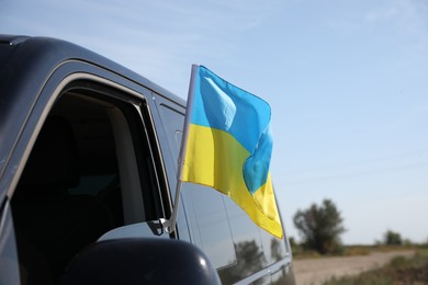Photo of National flag of Ukraine on car window outdoors, closeup