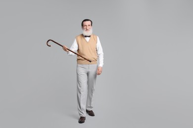Senior man with walking cane on light gray background