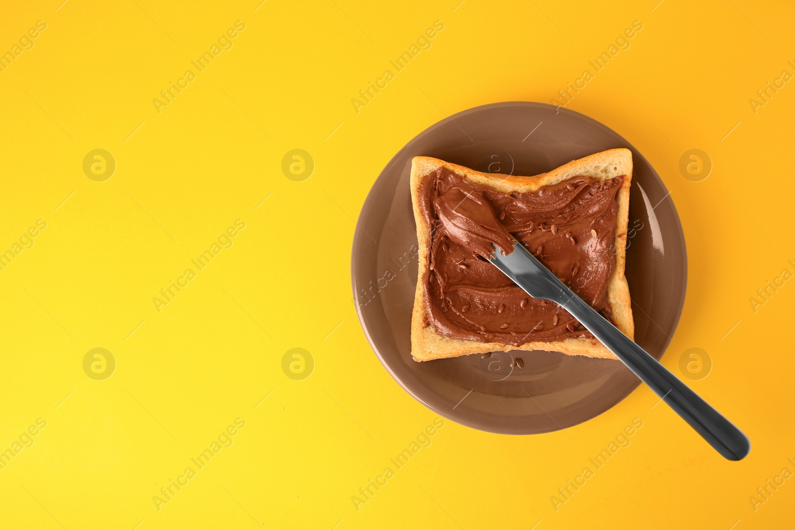 Photo of Tasty toast with chocolate paste and flax seeds on yellow background, top view. Space for text