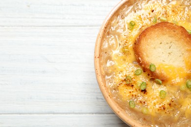 Tasty homemade french onion soup on white wooden table, top view. Space for text