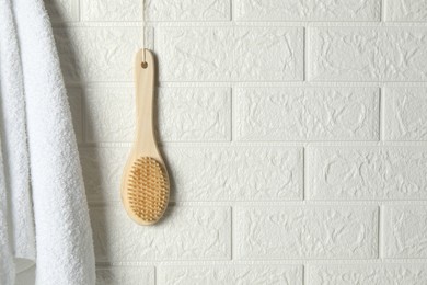 Photo of Bath accessories. Bamboo brush and terry towel on white brick wall, space for text