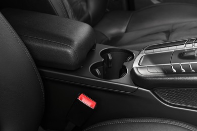 Photo of Cup holders and seat inside of modern black car, closeup