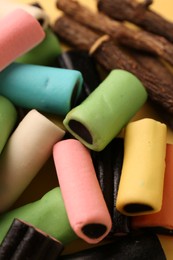 Tasty candies and dried liquorice roots on yellow background, closeup