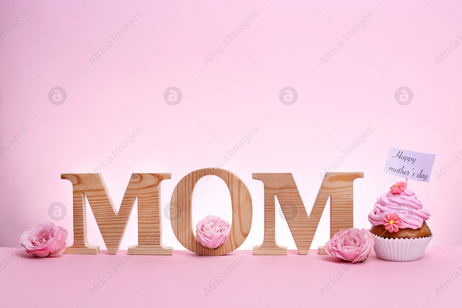 Photo of Tasty cupcake for Mother's Day and word MOM on color background