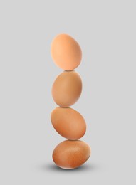 Stacked fresh chicken eggs against light grey background