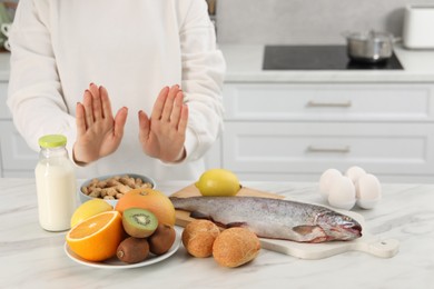 Photo of Woman suffering from food allergies refusing eat different fresh products at light table indoors, closeup