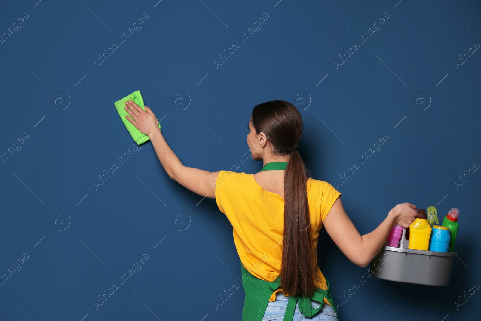 Photo of Woman with basin of detergents cleaning color wall