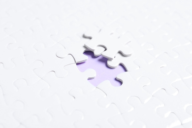 Photo of Blank white puzzle with separated piece on violet background