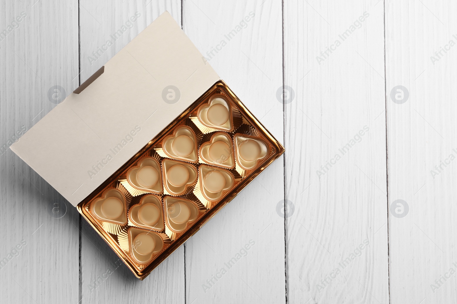 Photo of Empty box of chocolate candies on white wooden table, top view. Space for text