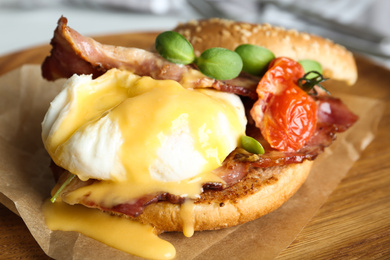 Photo of Delicious egg Benedict served on wooden plate, closeup