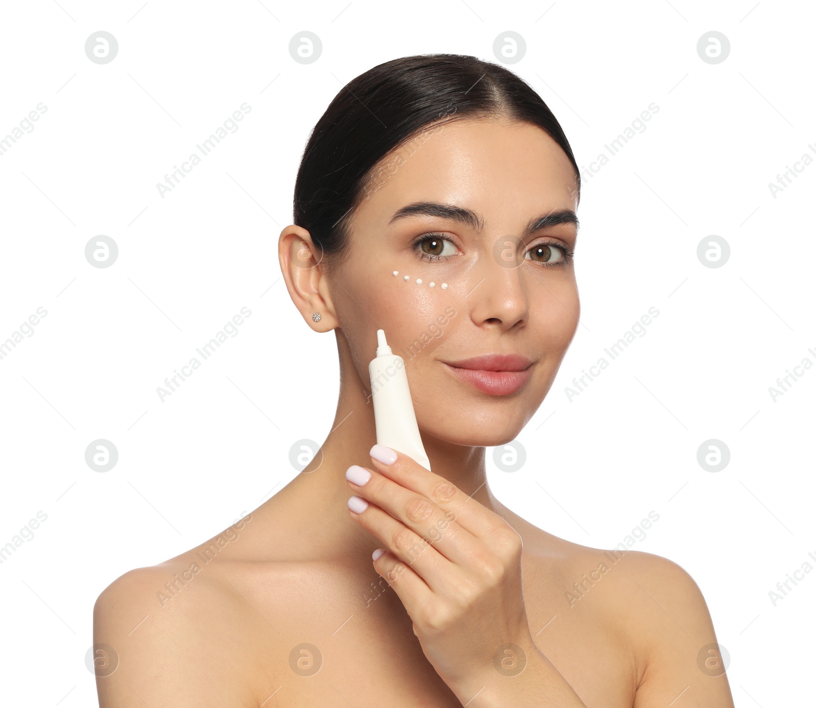 Photo of Beautiful young woman with cream on skin under eye against white background