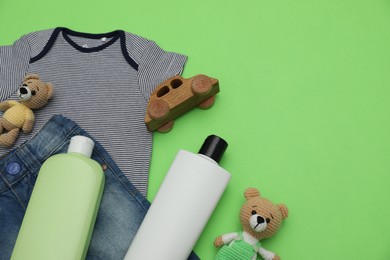 Photo of Bottles of laundry detergents, baby clothes and toys on light green background, flat lay. Space for text