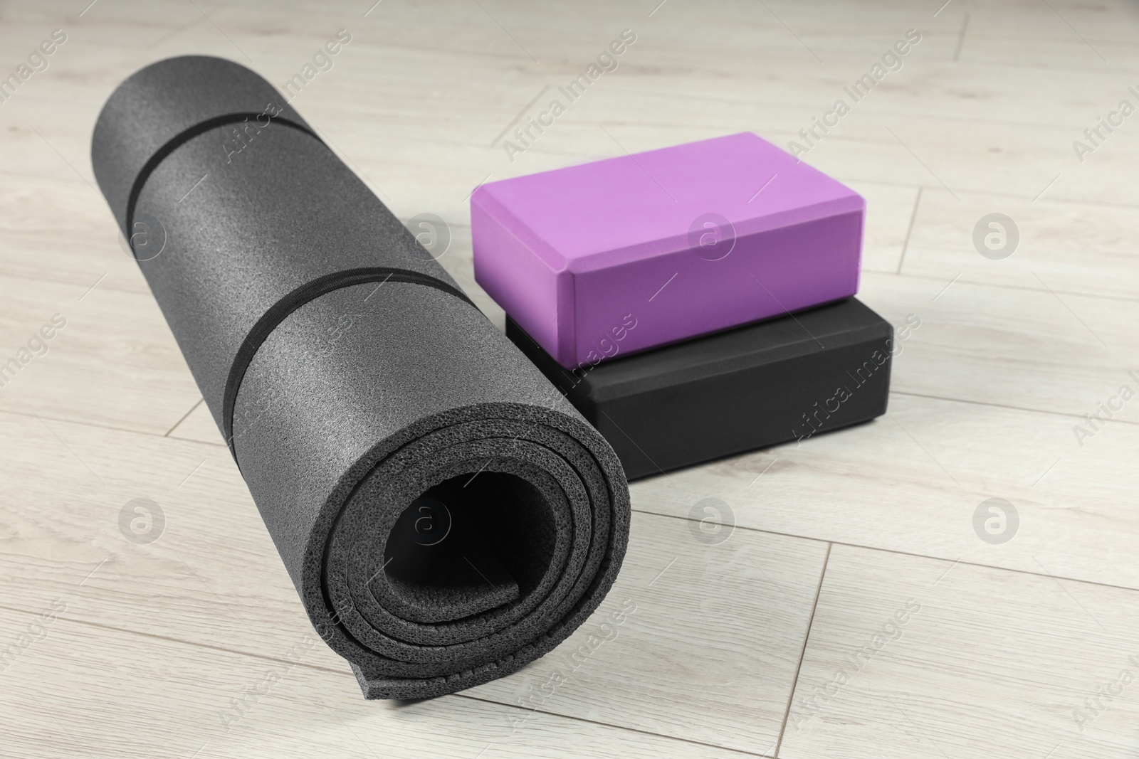 Photo of Exercise mat and yoga blocks on light wooden floor