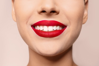 Beautiful young woman with red lips on color background, closeup