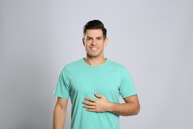 Photo of Happy healthy man touching his belly on light grey background