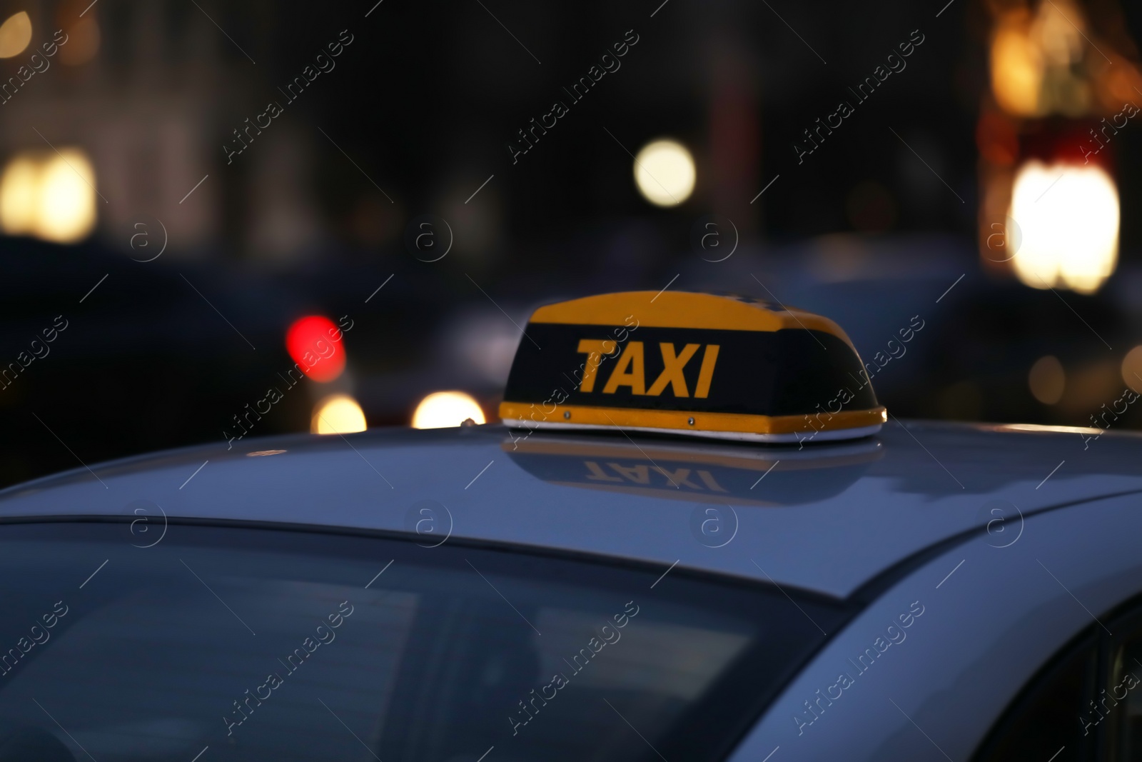 Photo of Taxi car with yellow checkered sign on city street in evening, closeup