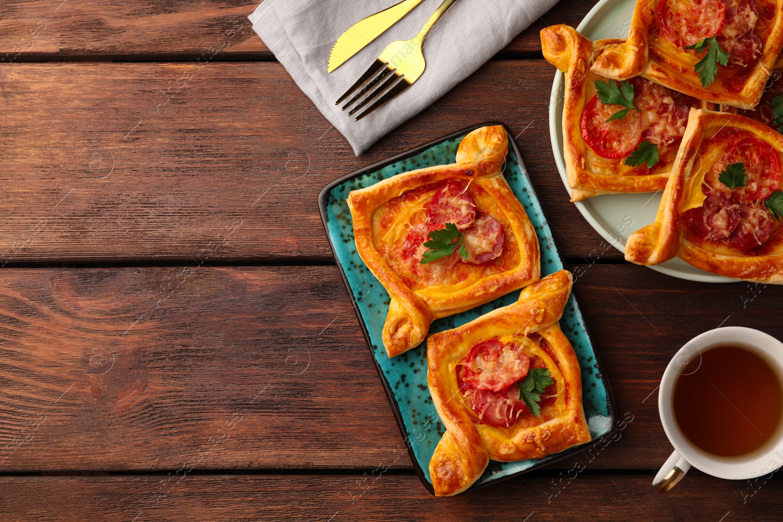 Photo of Fresh delicious puff pastry with cheese, tomatoes and parsley on wooden table, flat lay. Space for text