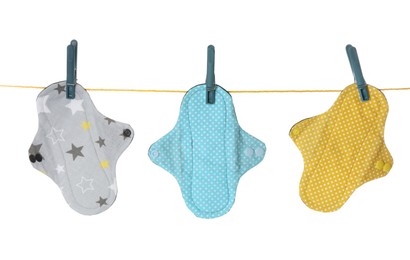 Many different cloth menstrual pads hanging isolated on white
