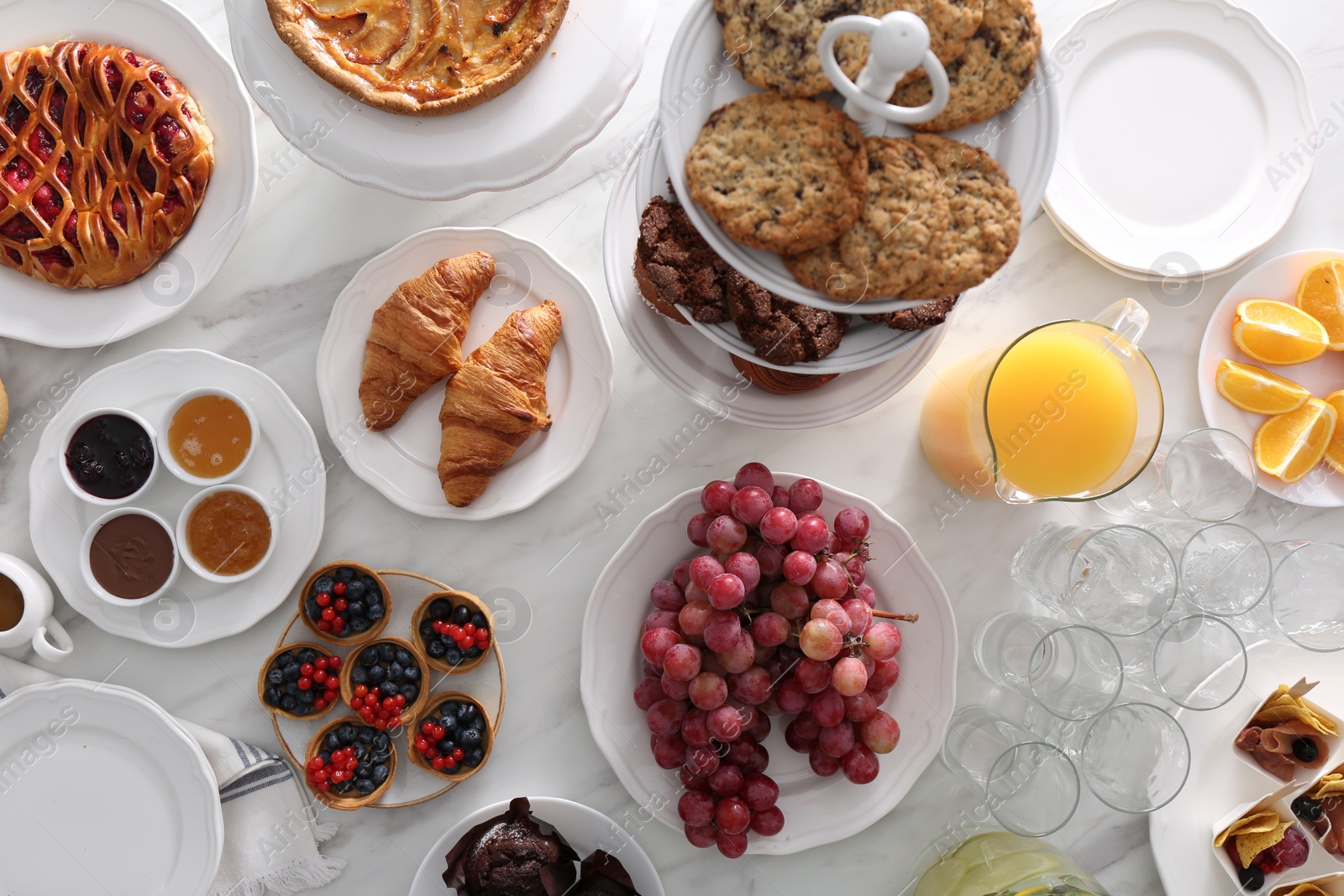 Photo of Variety of snacks on white marble table in buffet style, flat lay