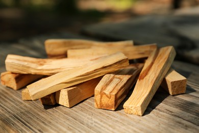 Palo santo sticks on wooden table outdoors, closeup