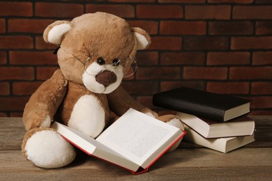Photo of Teddy bear with glasses and books on wooden table