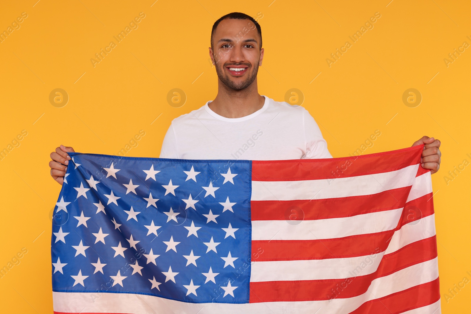 Photo of 4th of July - Independence Day of USA. Happy man with American flag on yellow background