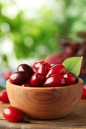 Photo of Fresh ripe dogwood berries in wooden bowl on table