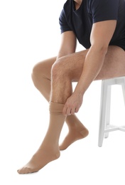 Photo of Man putting on compression stocking against white background, closeup