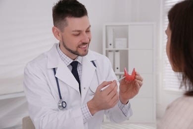 Photo of Doctor showing thyroid gland model to patient in hospital