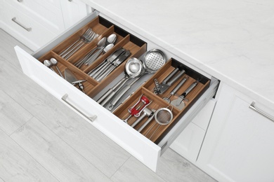 Photo of Open drawer with different utensils and cutlery in kitchen, above view