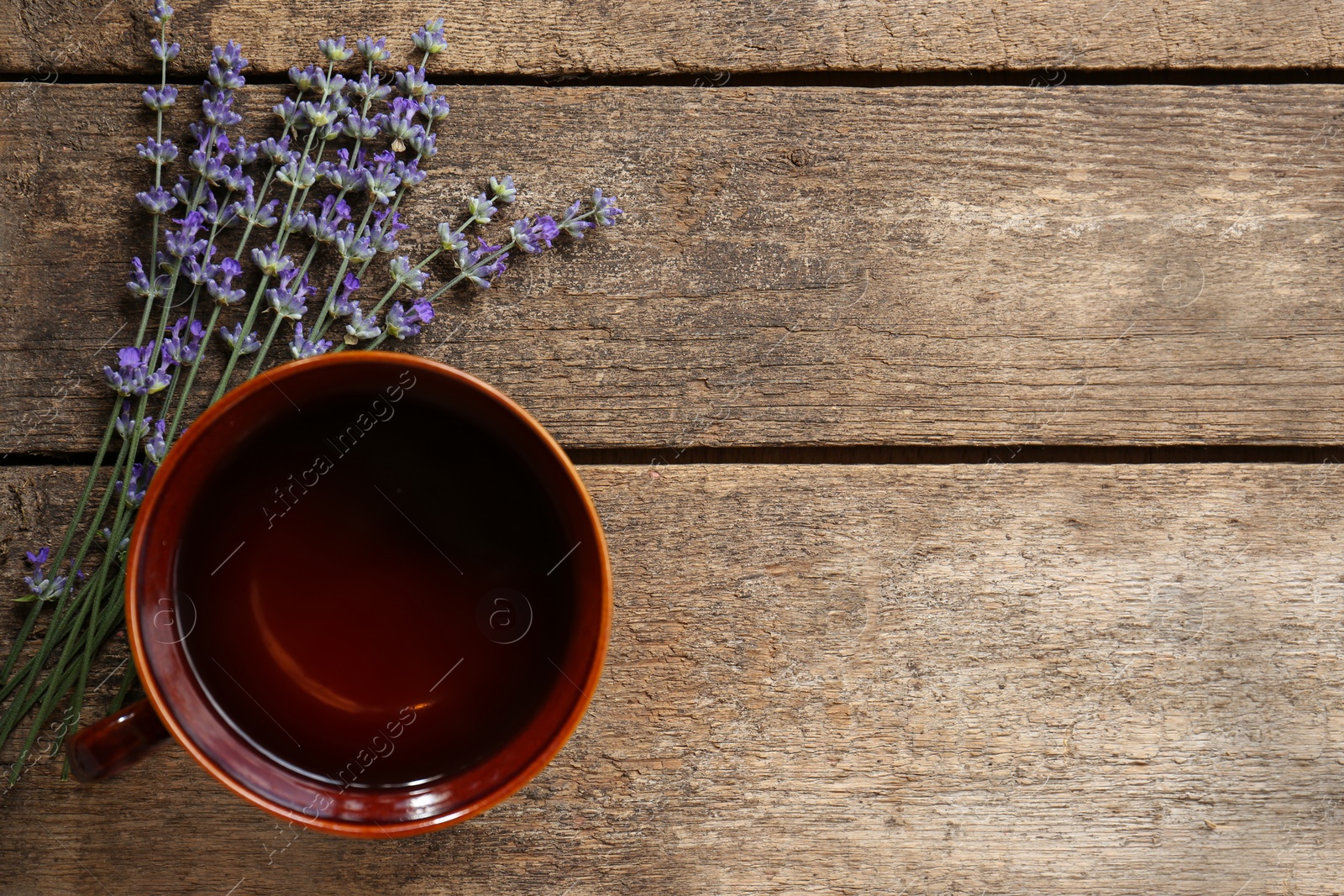 Photo of Tasty herbal tea and fresh lavender flowers on wooden table, flat lay. Space for text