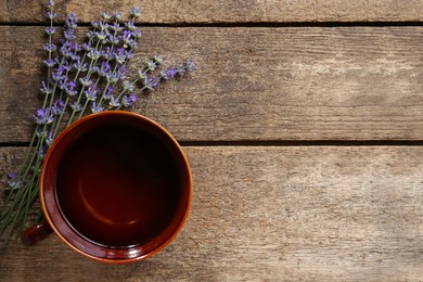 Photo of Tasty herbal tea and fresh lavender flowers on wooden table, flat lay. Space for text