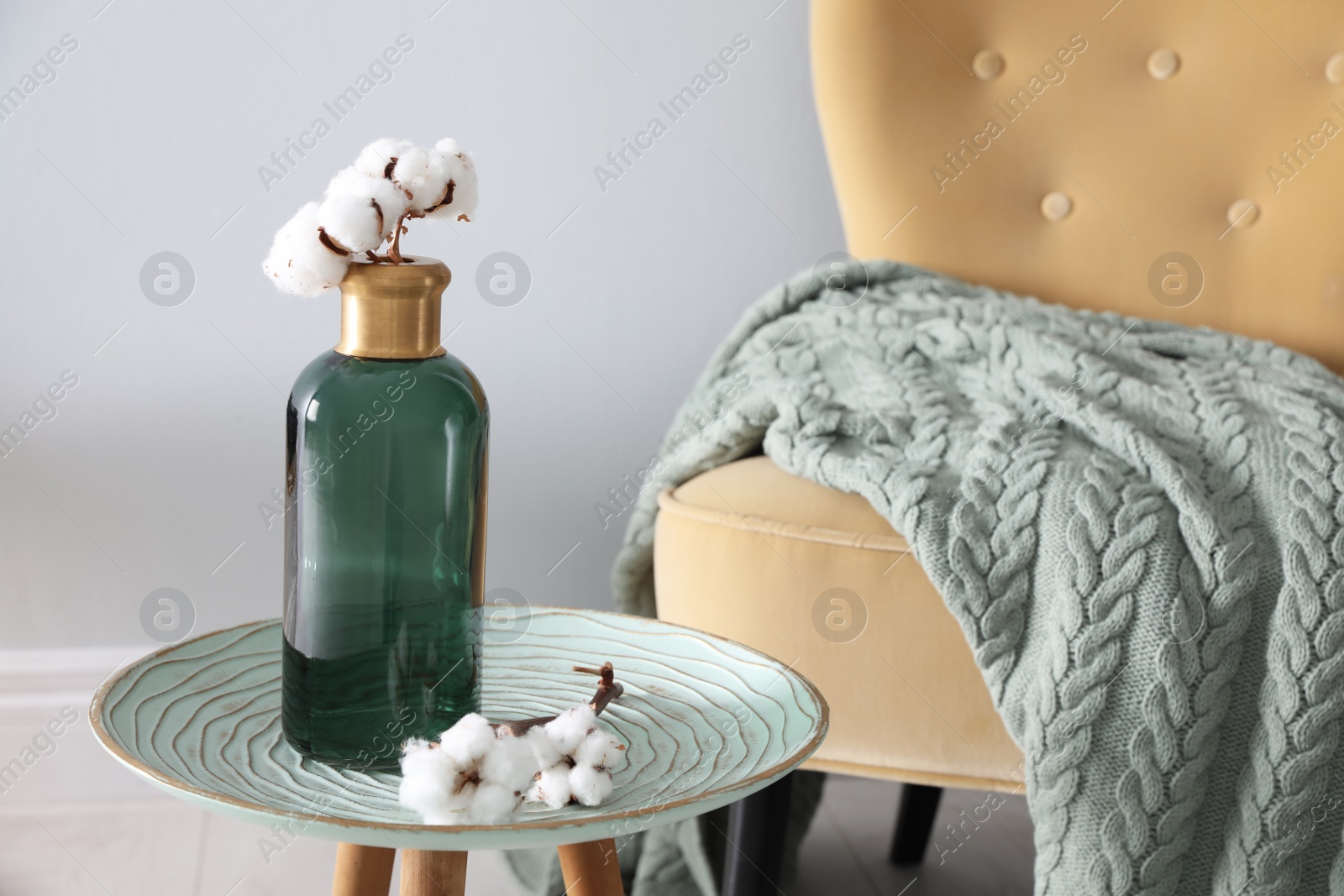 Photo of Soft knitted blanket on armchair in room. Home interior