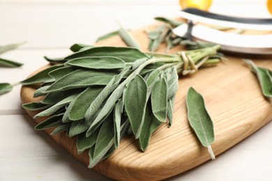 Photo of Wooden board with fresh green sage on table, closeup