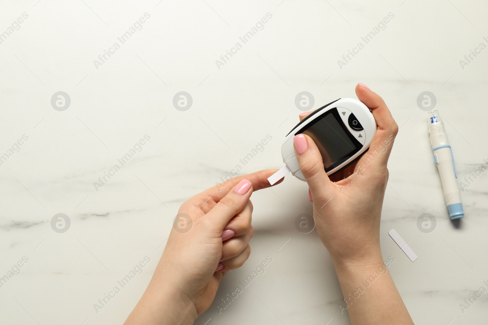 Photo of Diabetes. Woman checking blood sugar level with glucometer at white marble table, top view. Space for text