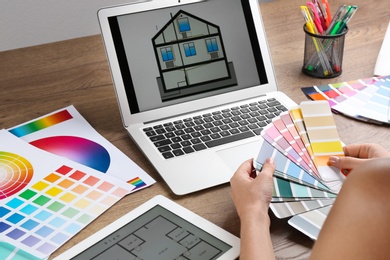 Photo of Woman with palette samples at wooden table, closeup