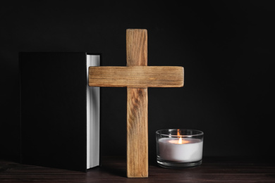 Photo of Cross, Bible and burning candle on wooden table. Christian religion