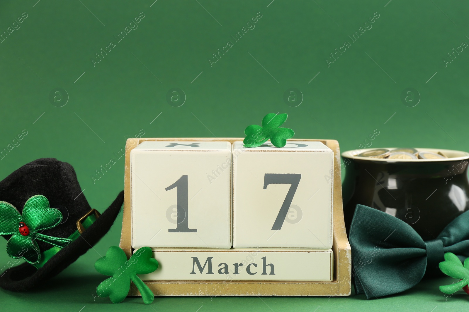 Photo of Leprechaun's hat, block calendar and St. Patrick's day decor on green background