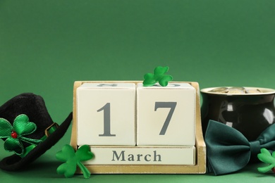 Photo of Leprechaun's hat, block calendar and St. Patrick's day decor on green background