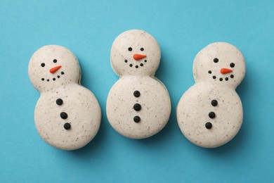 Photo of Beautiful snowman Christmas macarons on light blue background, flat lay