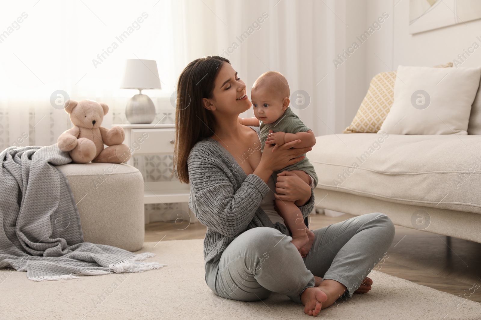 Photo of Young woman with her little baby on floor at home