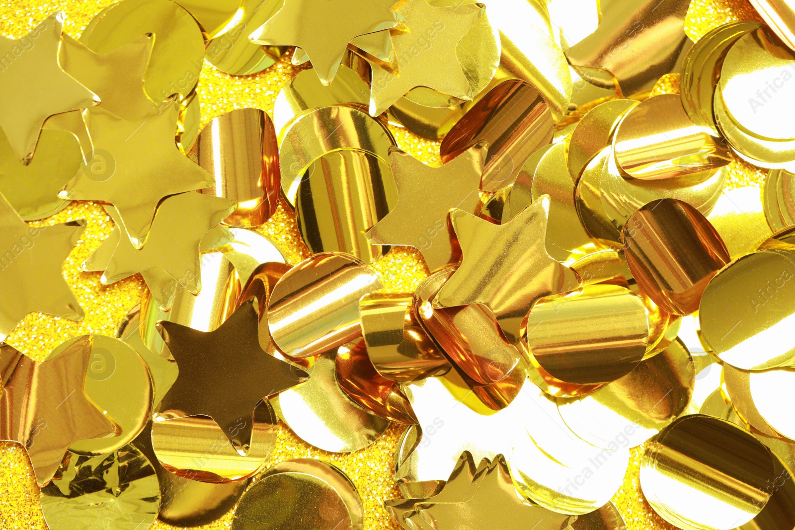 Photo of Beautiful golden confetti on shiny glitter, top view