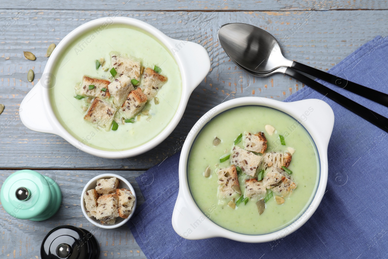 Photo of Delicious asparagus soup with croutons served on grey wooden table, flat lay