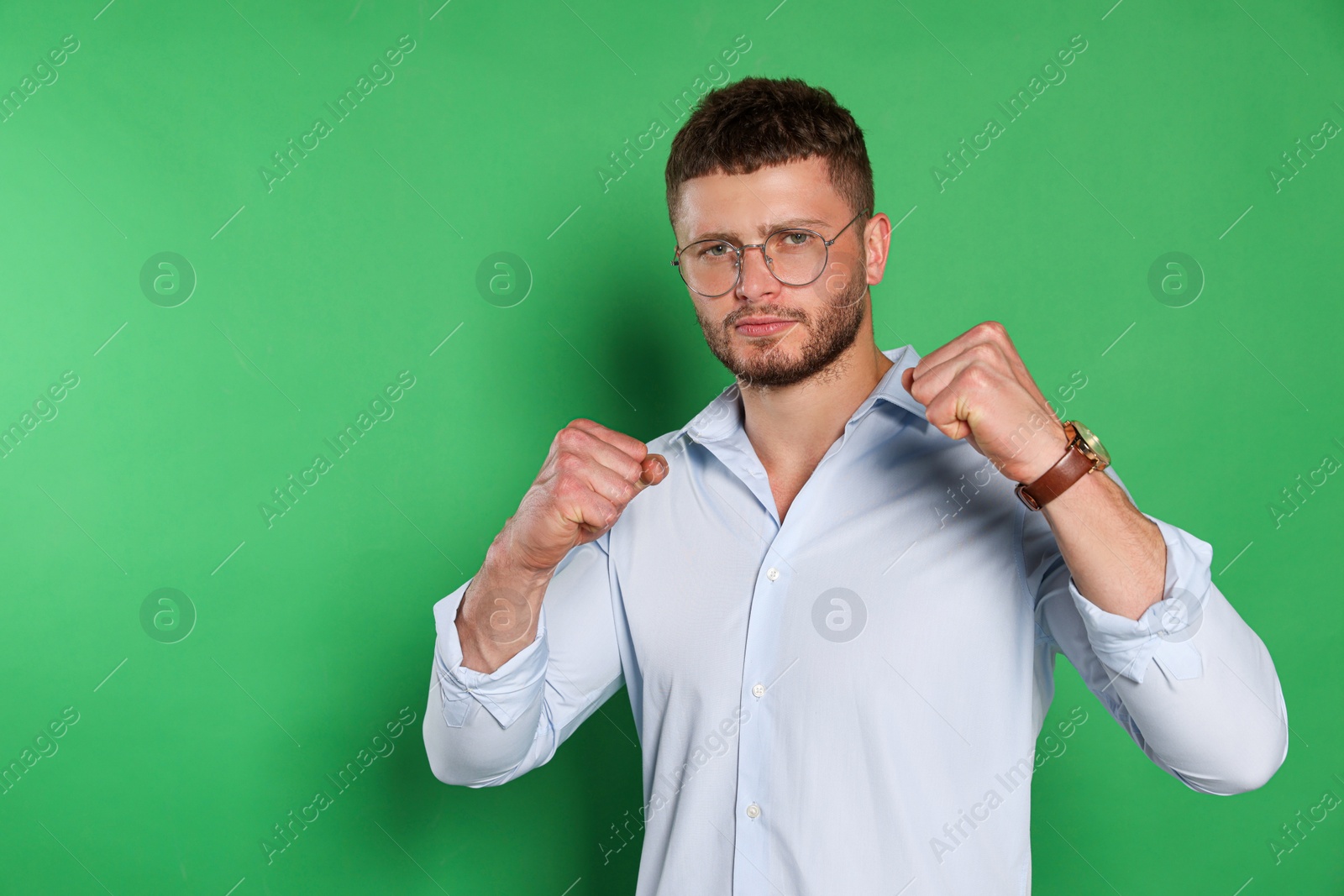 Photo of Young man ready to fight on green background, space for text