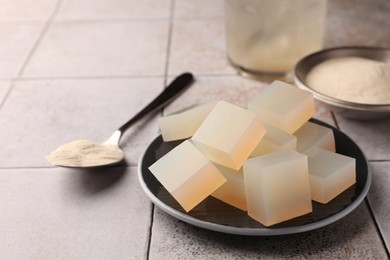 Photo of Agar-agar jelly cubes and powder on tiled surface, closeup