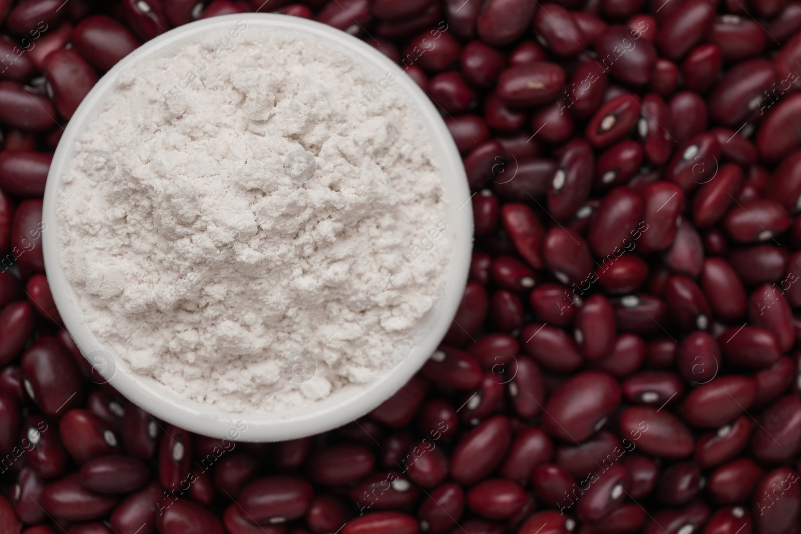 Photo of Bowl with kidney bean flour on brown seeds, top view. Space for text