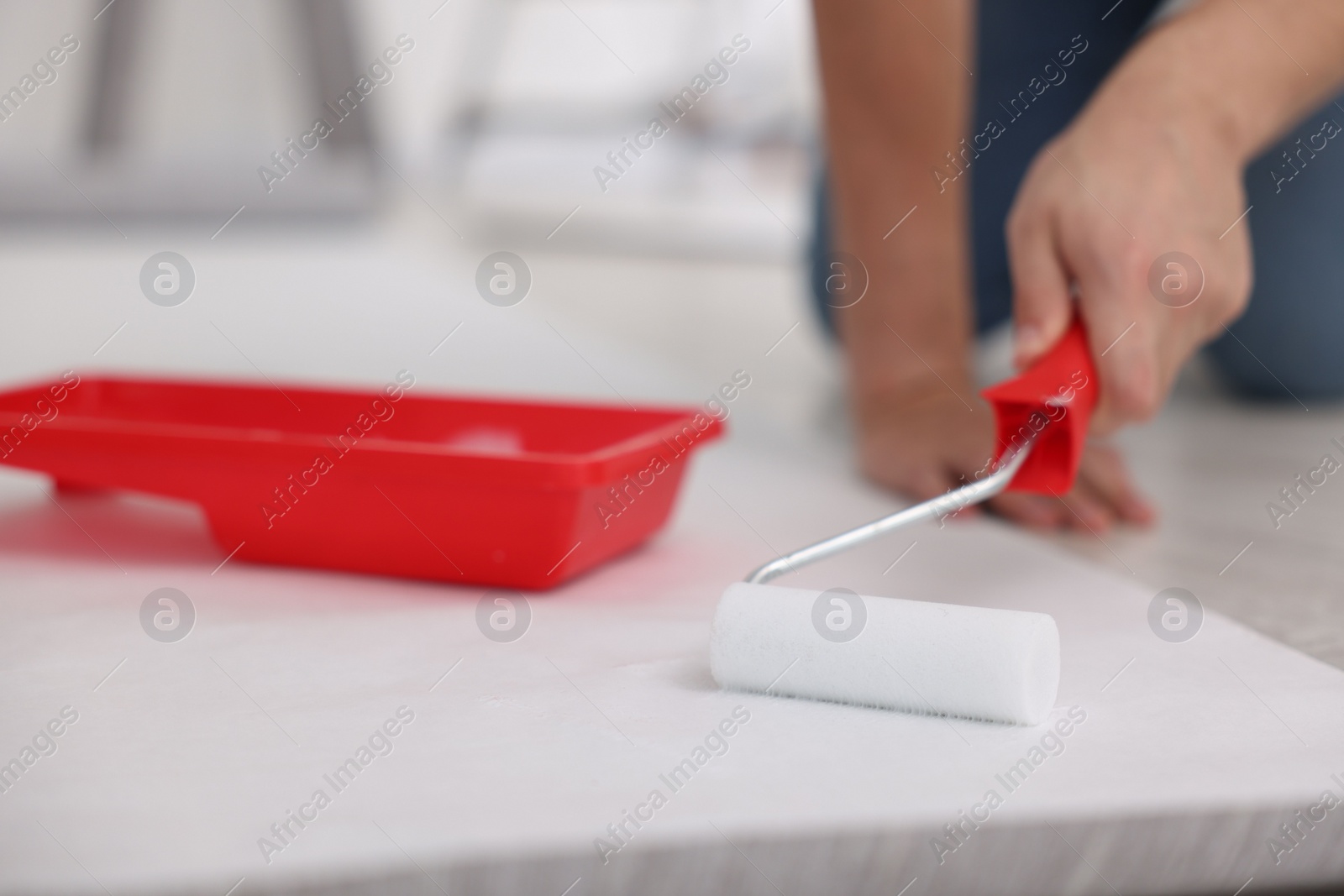 Photo of Man applying glue onto wallpaper sheet in room, closeup